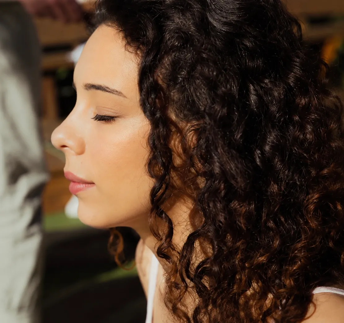 Mulher de perfil e de olhos fechados, ao sol, em meditação.
